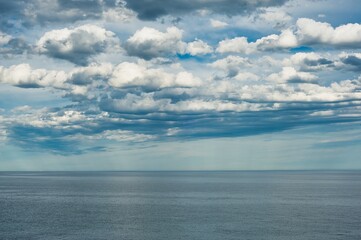 Naklejka na ściany i meble Blue sky with broken clouds in spring on the seashore