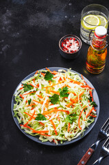 Coleslow cabbage salad with carrot on grey kitchen table. Top view, copy space