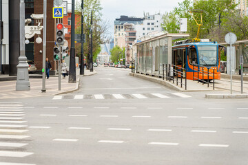 Obraz premium Empty crossroad and view of urban street with tram stop, traffic lights and pedestrian crossing