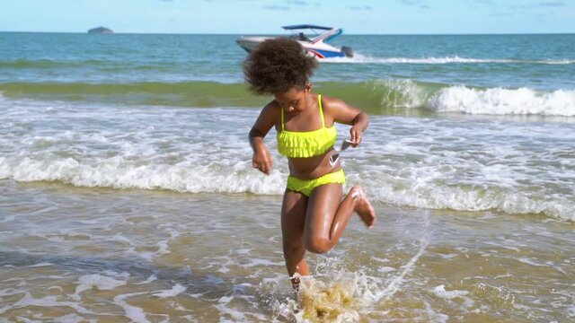 slow motion, african-American children jumping on the beach in summer vacation.
