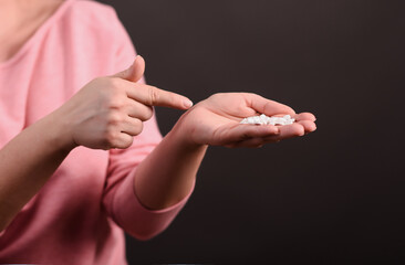Tablets in the palm of your hand. The woman points to the handful of pills in her hand. Close-up. On a black background.