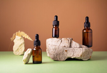 Naklejka premium Serum and oil cosmetic bottles on concrete stone podium with dry spikelet on brown and green background. Trendy natural organic healthy hair, face and body skin care