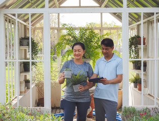 A middle-aged Asian couple is searching online for information on ornamental plants grown in nurseries.