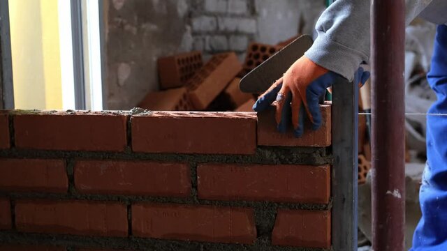 Construction worker building a brick wall. Man bricklaying. Mason laying bricks.