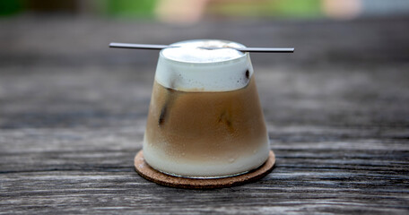 Fresh iced coffee in glass on wooden tray in coffee shop.