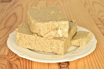 Several slices of vanilla halva on a white ceramic plate, close-up, on a wooden table.