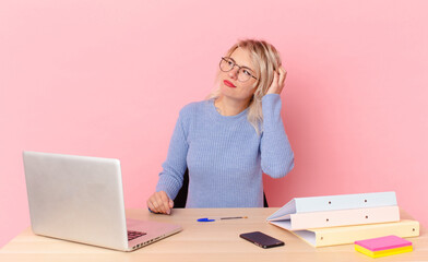 blonde pretty woman young pretty woman feeling puzzled and confused, scratching head. workspace...