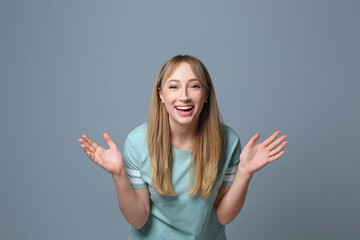 Beautiful young woman laughing on grey background. Funny joke