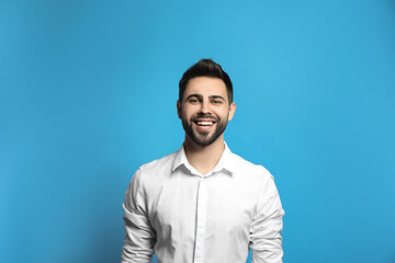 Young man laughing on light blue background. Funny joke