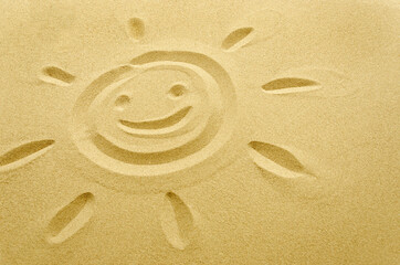 Fototapeta na wymiar face of smiling sun drawn in sand, empty space
