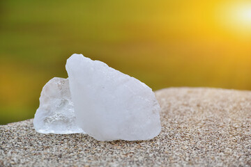 Closeup view of alum cubes on stone marble floor with sunlight in the sunset background.