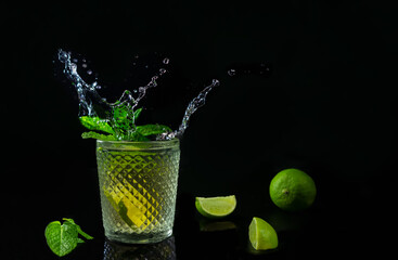 Fresh summer mojito cocktail with splashing isolated on dark background.Party rum refreshing drink with fresh limes and mint.