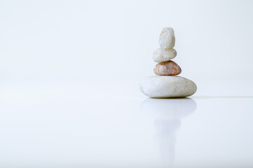 Fototapeta na wymiar reflected pyramid of zen stones on a white background