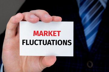 businessman holding a card with text MARKET FLUCTUATIONS
