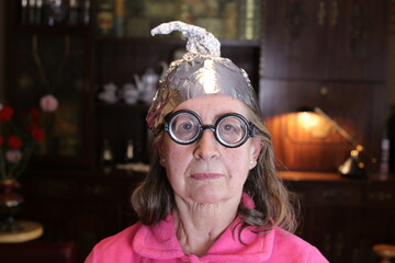 Distrustful senior woman wearing weird tinfoil hat
