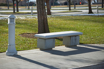 Closeup shot of a stone bench next to a street lamp in the park