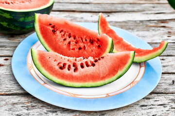 Slices of ripe fresh watermelon on wooden table outdoor. Healthy eating summertime concept. Organic fruits.