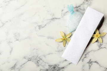 Scented sachets, vanilla and flowers on white marble table, flat lay. Space for text