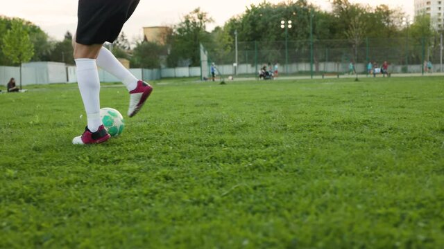 Freestyler makes zidane's feint. Woman footballer plays football, a training day on the grass field in the the evening park.
