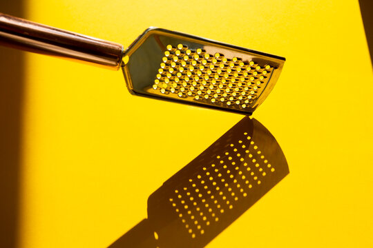 small kitchen grater for cheese, vegetables and small products on yellow background