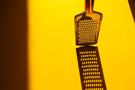 small kitchen grater for cheese, vegetables and small products on yellow background