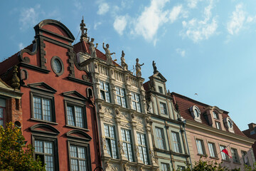 Fototapeta premium A close up of the facades of tall building in the middle of Old Town in Gdansk, Poland. The buildings have many bright colors, they are richly decorated. City tour. Clear day.