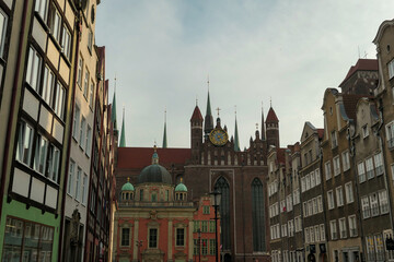Obraz premium A close up of the facades of tall building in the middle of Old Town in Gdansk, Poland. The buildings have many bright colors, they are richly decorated. City tour. Clear day.