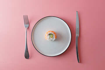 Diet food concept, one Philadelphia roll on plate with knife and fork