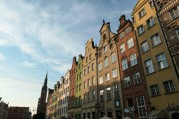 A close up of the facades of tall building in the middle of Old Town in Gdansk, Poland. The buildings have many bright colors, they are richly decorated. High tower of Town Hall. City tour. Clear day.