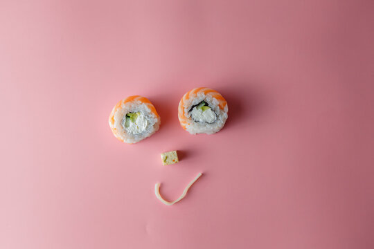 Sushi roll and noodle emoticon. Smiling face on a pink background. The concept of good mood and proper nutrition. Food is enjoyable