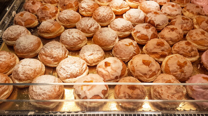 A massive counter filled with donuts covered with icing and filled with rose marmalade. The donuts are kept in a special counter, keeping them warm inside.