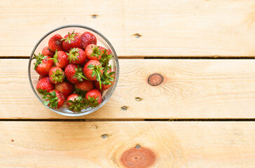 Strawberry in glass bowl on wooden background
