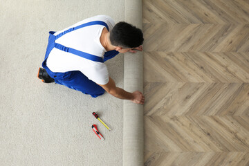 Worker rolling out new carpet indoors, above view