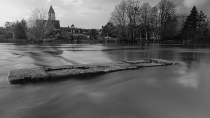 En noir et blanc, Sarthe en pose longue au niveau des fondation d'un ancien pont à Noyen sur Sarthe face au village