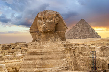 Fototapeta na wymiar Great sphinx and pyramids. Egypt Cairo. Landscape with Egyptian pyramids, Great Sphinx and silhouettes Ancient symbols and landmarks of Egypt in golden sunlight. Sphinx in Giza pyramid complex