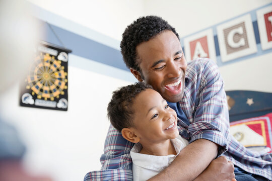 Playful father embracing son in bedroom