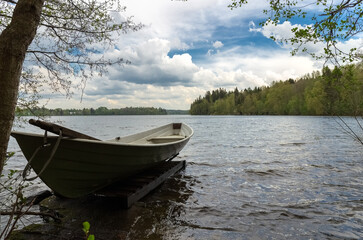 Wooden boat on the shore of the lake. Summer outdoor recreation concept.