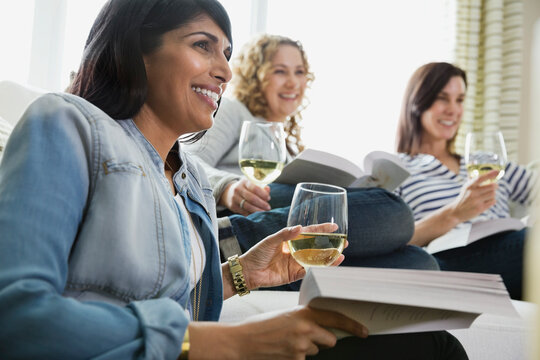 Smiling mature women with wineglasses at home book club