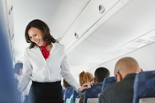 Flight attendant talking to passengers in airplane