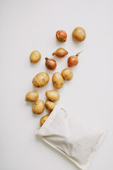 Potatoes and onion in eco-bag on white. organic healthy food background. Flat lay, top view, copy space. Grocery shopping food supermarket and zero waste concept
