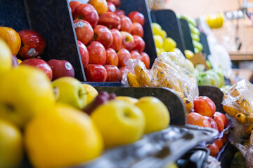 Close-up of colorful fruit stand with apples, small bananas, and more