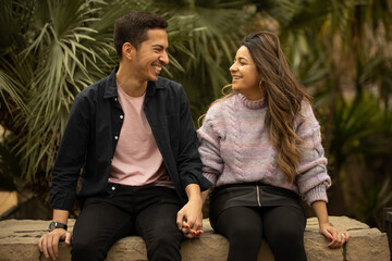 A couple in a romantic moment smiling and looking each other in a park