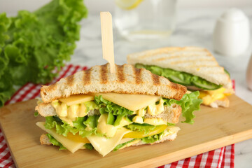 Wooden board with tasty cheese sandwich on table