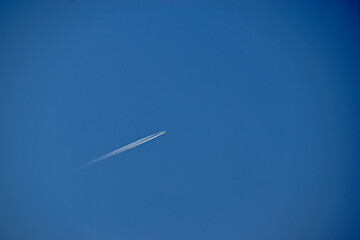 A distant plane flying across the blue sky