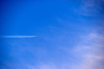 A distant plane flying across the blue sky