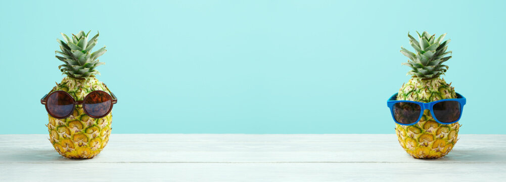 Summer Holidays Vacation And Beach Party Concept. Pineapple With Sunglasses On Wooden Table Over Blue Background.