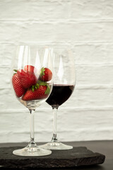 Ripe juicy red beautiful strawberry close-up is an appetizing fresh snack paired with glass of red wine