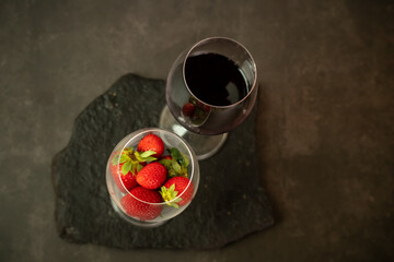 Ripe juicy red beautiful strawberry close-up is an appetizing fresh snack paired with glass of red wine © S.Kubarev