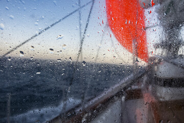 sailing yacht in heavy weather with storm and rain , sailing with yellow Storm jib