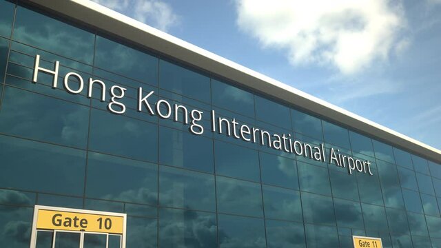 Landing airplane reflects in the modern windows with Hong Kong International Airport text